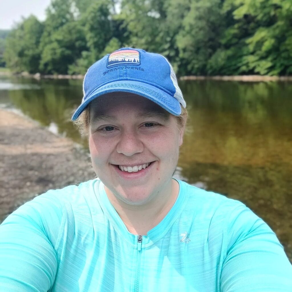 a person smiles for a selfie next to a river