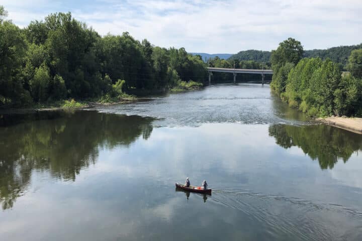 two people paddle a canoe in front of a bridge