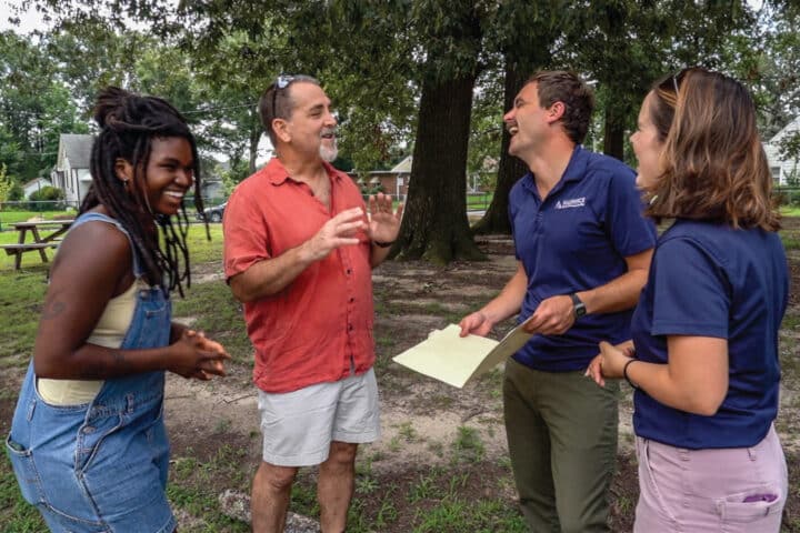 four people laugh while talking to each other