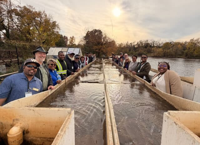 a group of people gather around a long structure holding water