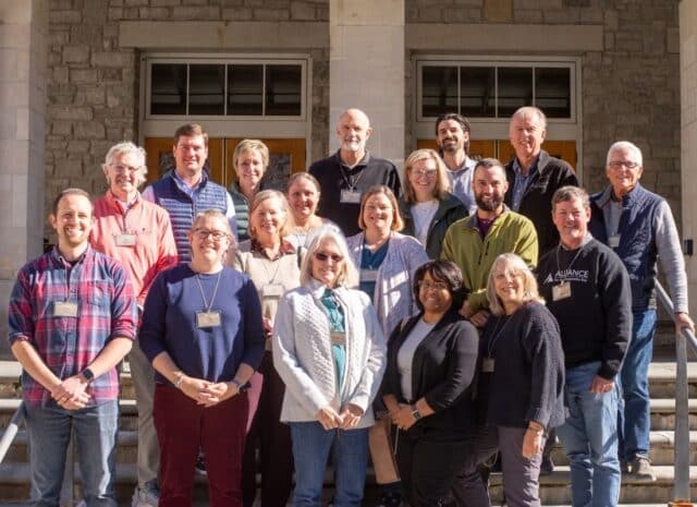 a group of people smile for a photo standing on steps