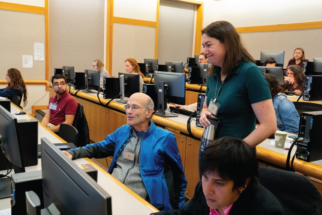 a person watches as people use computers