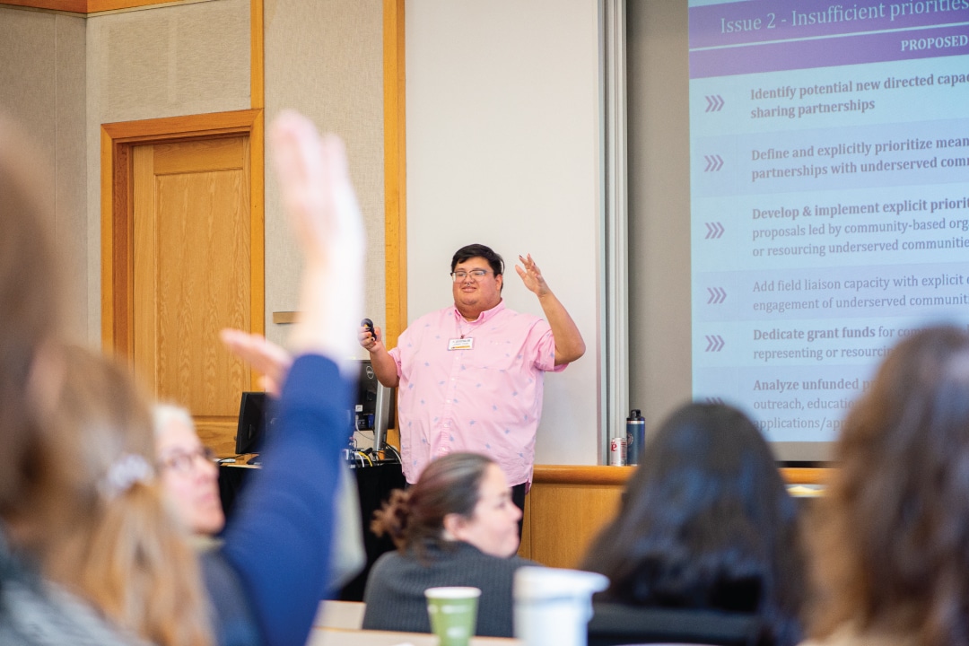 a person presents to people while they raise their hands