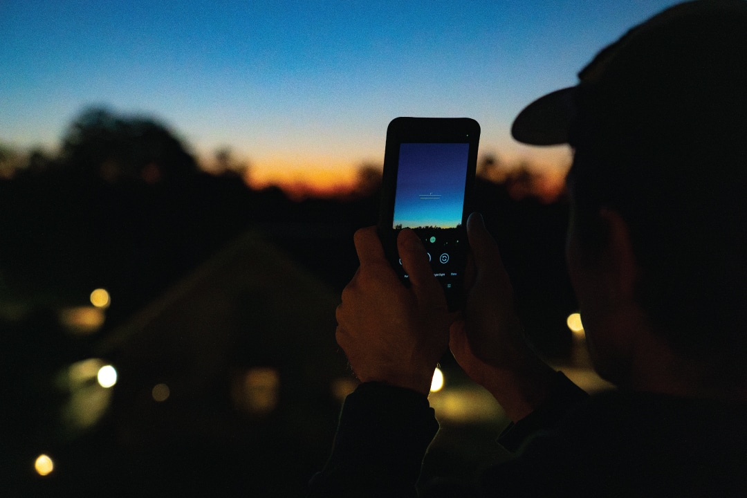 a person holds a phone facing the night sky