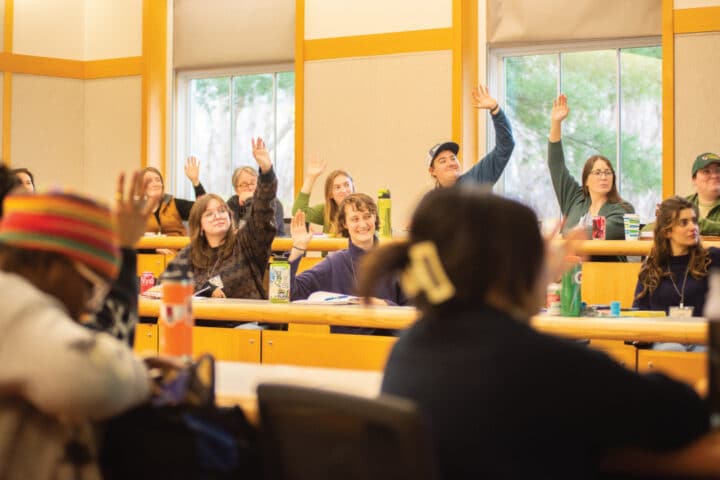 people sitting at tables raise their hands