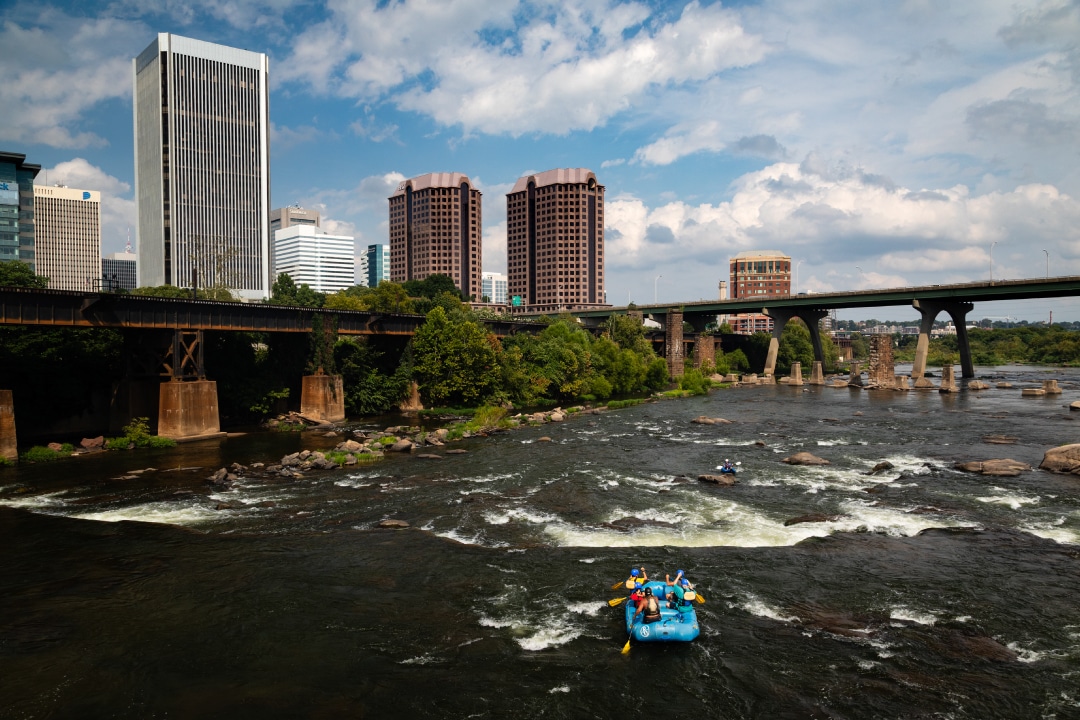 people paddle down a river in an urban environment